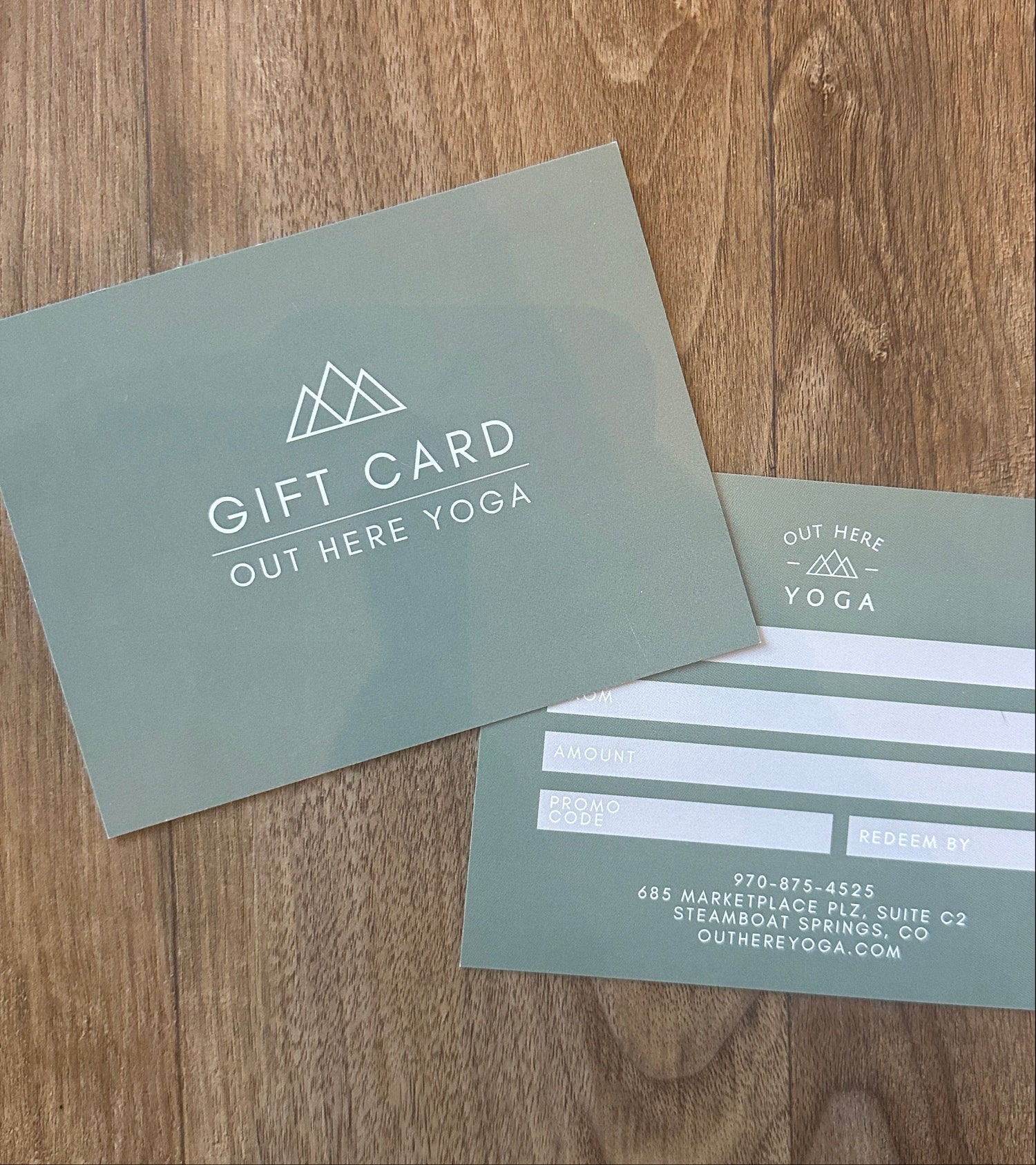 Two green gift cards on a wooden surface