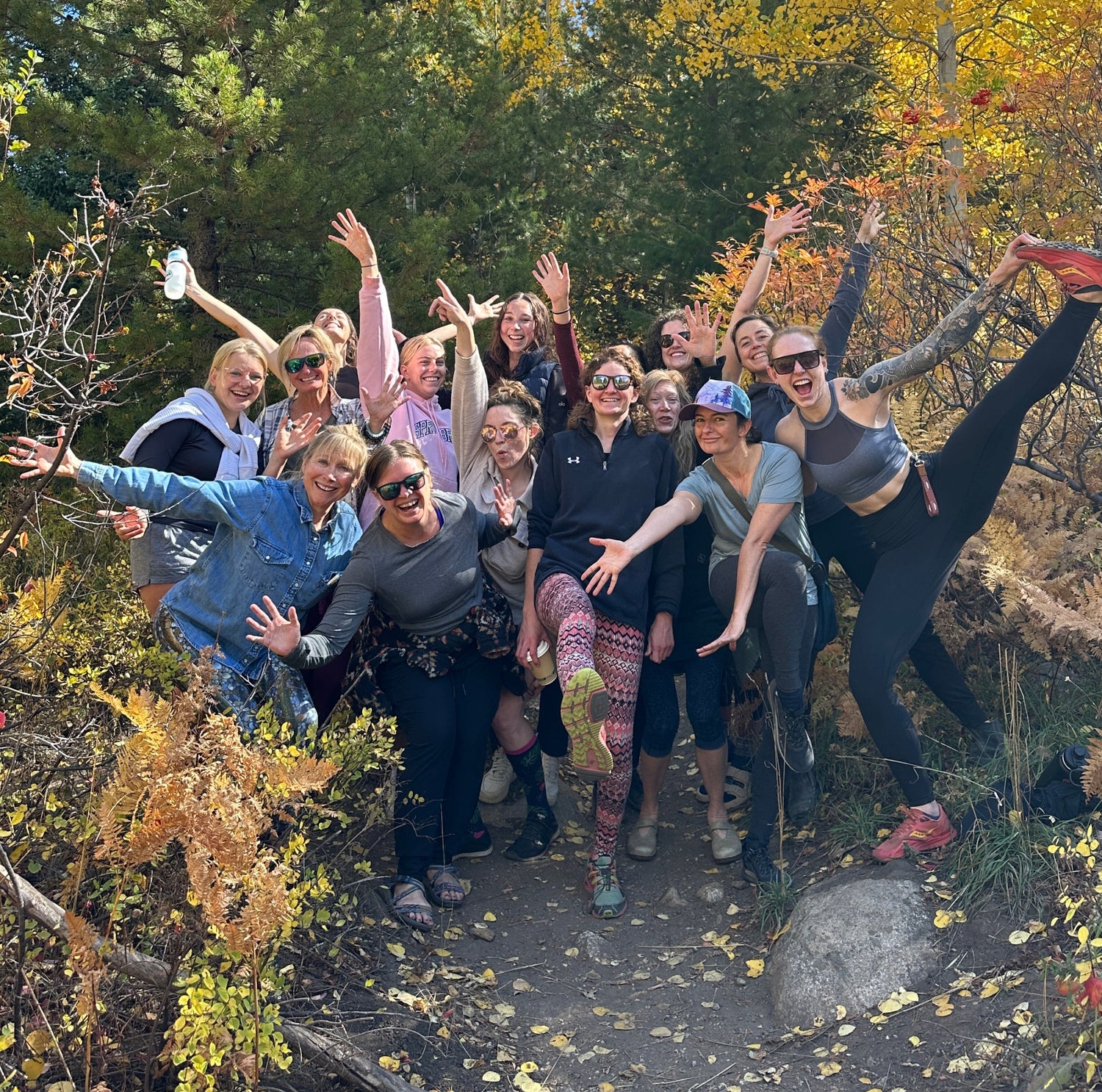 Group of people posing for a photo in a forest with autumn foliage